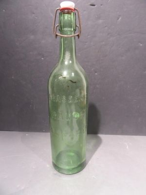 une bouteille en verre verte avec un bouchon rouge posée sur une table