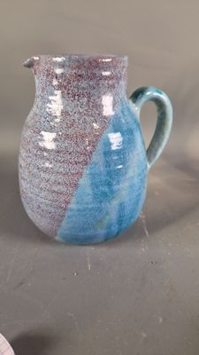 a blue and white pitcher sitting on a table next to a cup