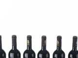 six bottles of wine lined up in a row on a white surface