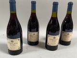 quatre bouteilles de vin sont alignées sur une surface blanche