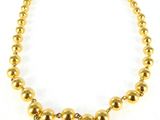a close up of a gold necklace on a white background
