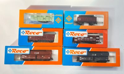 quatre boîtes contenant des trains miniatures, posées sur une surface blanche
