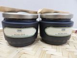 two jars of blueberry jam with a wooden spoon sitting on a table