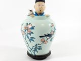 a small figurine of a boy sitting on a vase