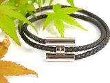 two black leather bracelets with silver clasps on a white surface