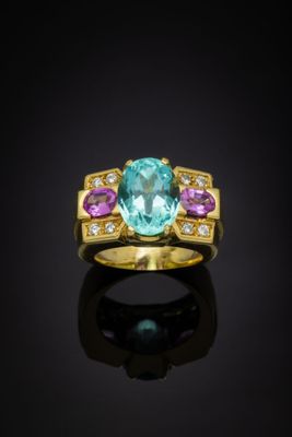 a gold ring with a blue topaz and pink sapphires