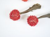 three red beaded hair clips are on a white surface