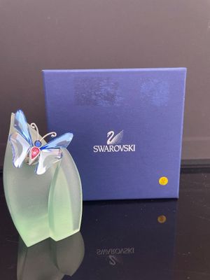 un vase en verre orné d'un papillon, à côté d'une boîte bleue
