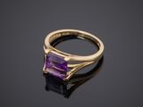 a gold ring with an amethorate stone on a black surface