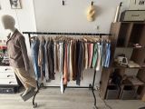 a mannequin standing in front of a rack of clothes