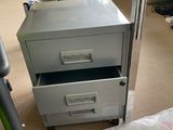 a metal filing cabinet with a glass top and two drawers