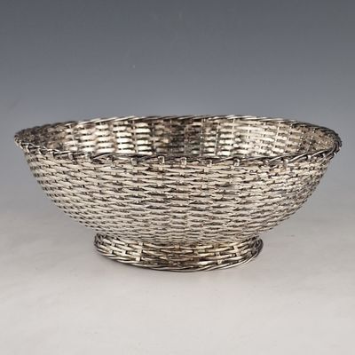 an antique silver plated bowl on a stand on a white surface