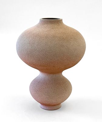 un petit vase posé sur une surface blanche