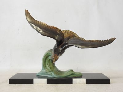 bronze sculpture of a bird flying over a wave on a marble base