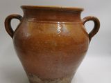 un vase marron muni de deux anses, sur un fond blanc