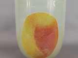 a glass cup with a peach on it sitting on a table