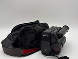 a black camera and a black bag on a white surface