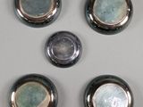 four silver and blue plates are arranged on a white surface