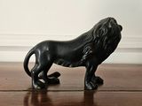 a black lion figurine sitting on a wooden floor