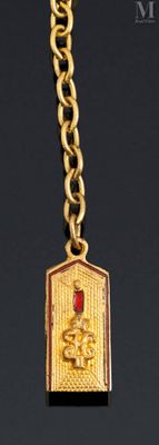 a gold necklace with a red rose on it