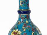 un vase bleu avec des fleurs sur un fond blanc