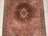 un vieux tapis orné d'un motif en losanges, posé sur le sol