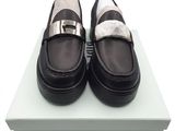 des mocassins noirs et blancs posés sur une boîte, sur une surface blanche