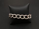 un gros plan d'un bracelet à chaîne en argent posé sur un coussin noir