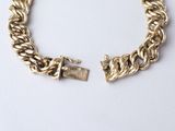 a close up of a gold chain bracelet on a white surface