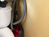 des toilettes blanches équipées d'un système d'aspiration, situées dans un coin de la salle de bains