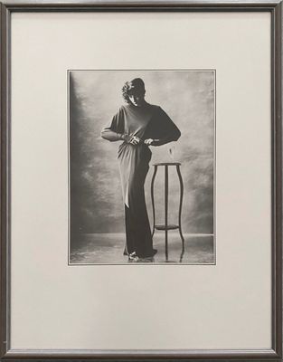 an old black and white photo of a woman leaning on a chair