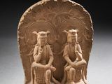 une photo représentant une sculpture en pierre représentant deux personnes assises sur une chaise