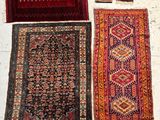 three oriental rugs are laid out on a white surface