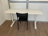 un bureau blanc avec une chaise noire devant une fenêtre
