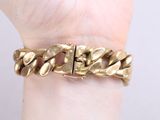 someone is holding a gold bracelet that has a chain on it