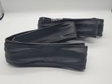une paire de chaussures en cuir noir posées sur une surface blanche, avec une lampe en arrière-plan