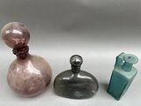 three glass bottles sitting next to each other on a white surface