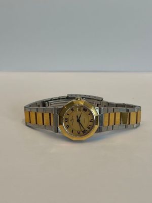 une montre-bracelet en or et en argent posée sur une surface blanche
