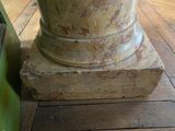 a close up of a stone column on a wooden floor