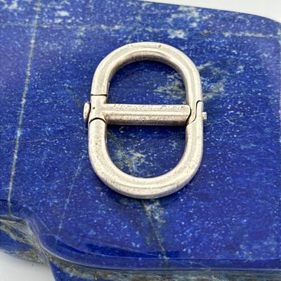 un gros plan d'une boucle métallique posée sur une pierre bleue
