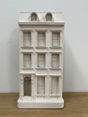 doll house on a wooden table with a white wall behind it