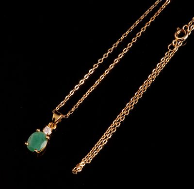 un gros plan d'un collier en or orné d'une pierre verte