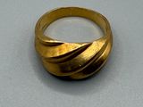 une image représentant une bague en or posée sur une surface grise