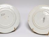 two white plates with gold rims are sitting on a white surface