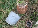 un seau et une casserole posés dans l'herbe, près d'un trottoir