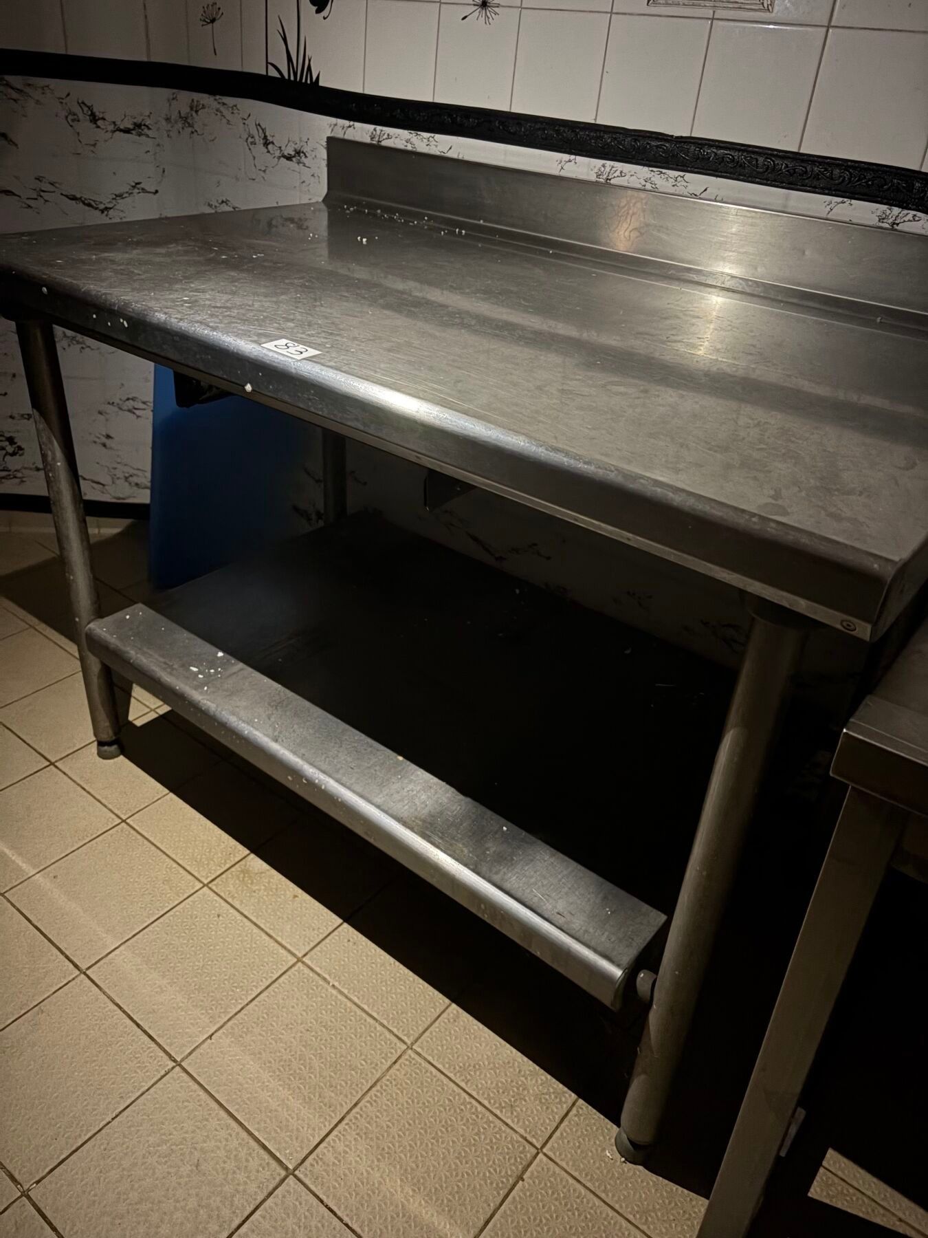 Une table inox à dosseret et plateau entre jambe.
