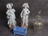 deux figurines placées à côté d'un vase en verre