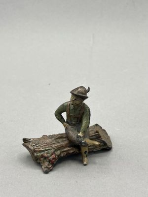 figurine of a man sitting on a log with a dog