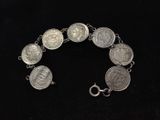 a close up of a silver bracelet with coins on it