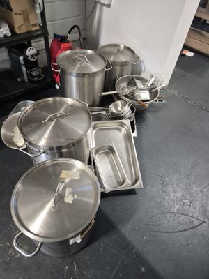 de nombreuses casseroles et poêles posées par terre dans la cuisine